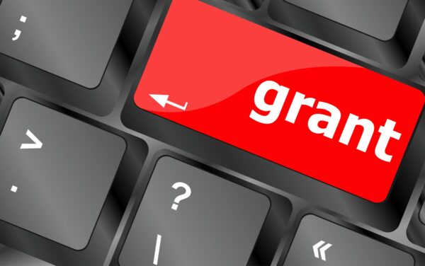 close up photo of a computer keyboard with the enter key replaced with a red grant button.